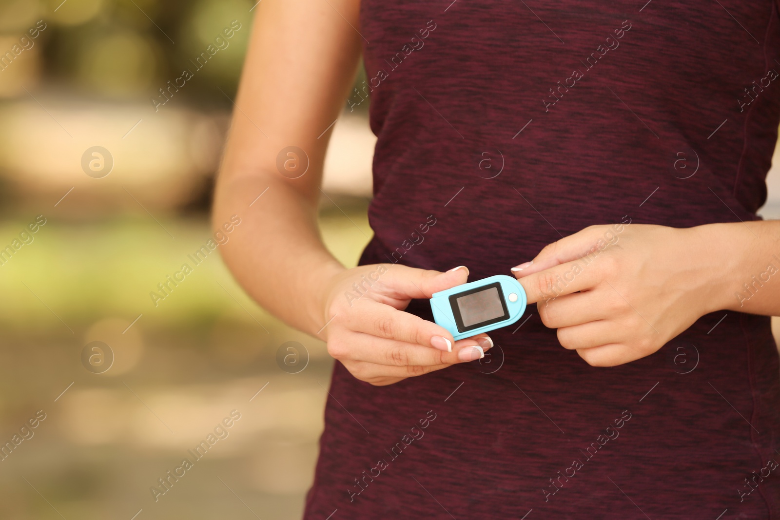 Photo of Young woman checking pulse outdoors on sunny day