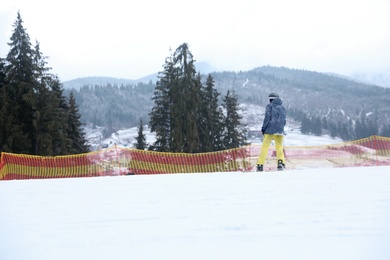 Snowboarder on slope at resort. Winter vacation