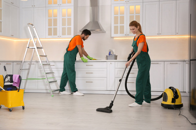 Photo of Team of professional janitors cleaning modern kitchen