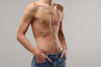 Photo of Shirtless man with slim body on grey background, closeup