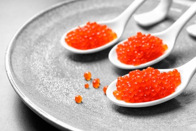 Photo of Spoons with delicious red caviar on plate