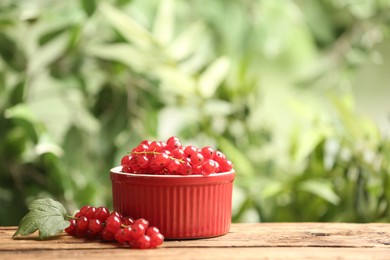Ripe red currants on wooden table against blurred background. Space for text