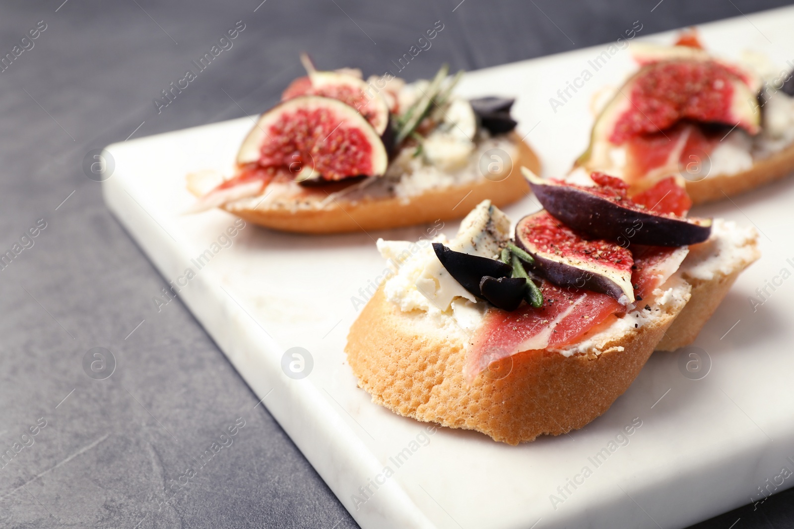 Photo of Sandwich with ripe fig, prosciutto and cheese on white board, closeup