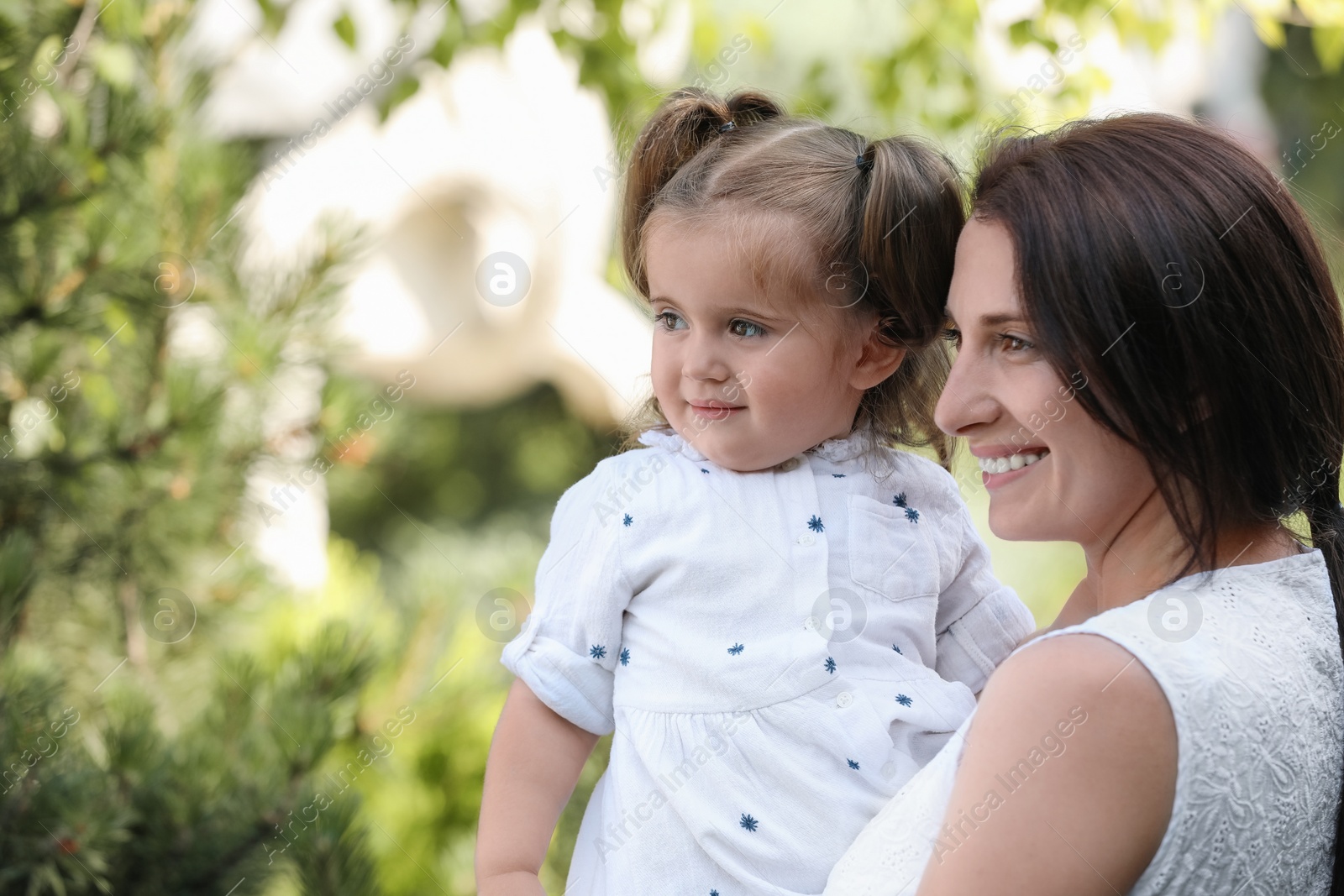 Photo of Portrait of happy mother with her cute daughter in park, space for text