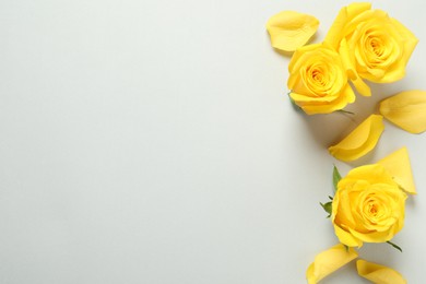 Photo of Beautiful yellow roses on light grey background, flat lay. Space for text