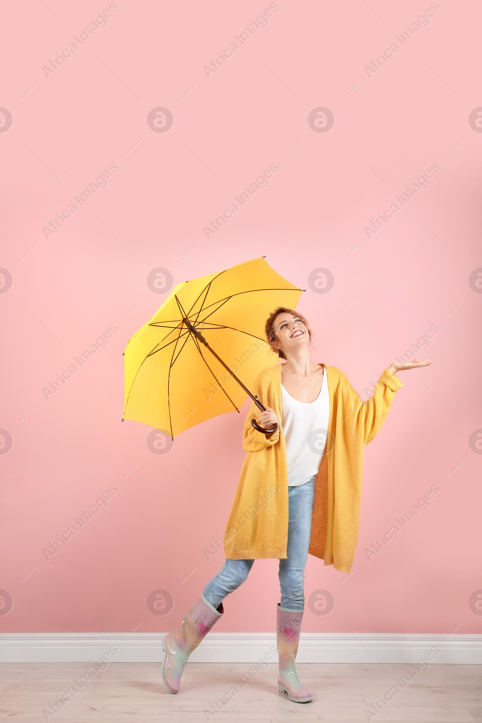 Photo of Woman with yellow umbrella near color wall