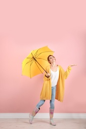 Woman with yellow umbrella near color wall