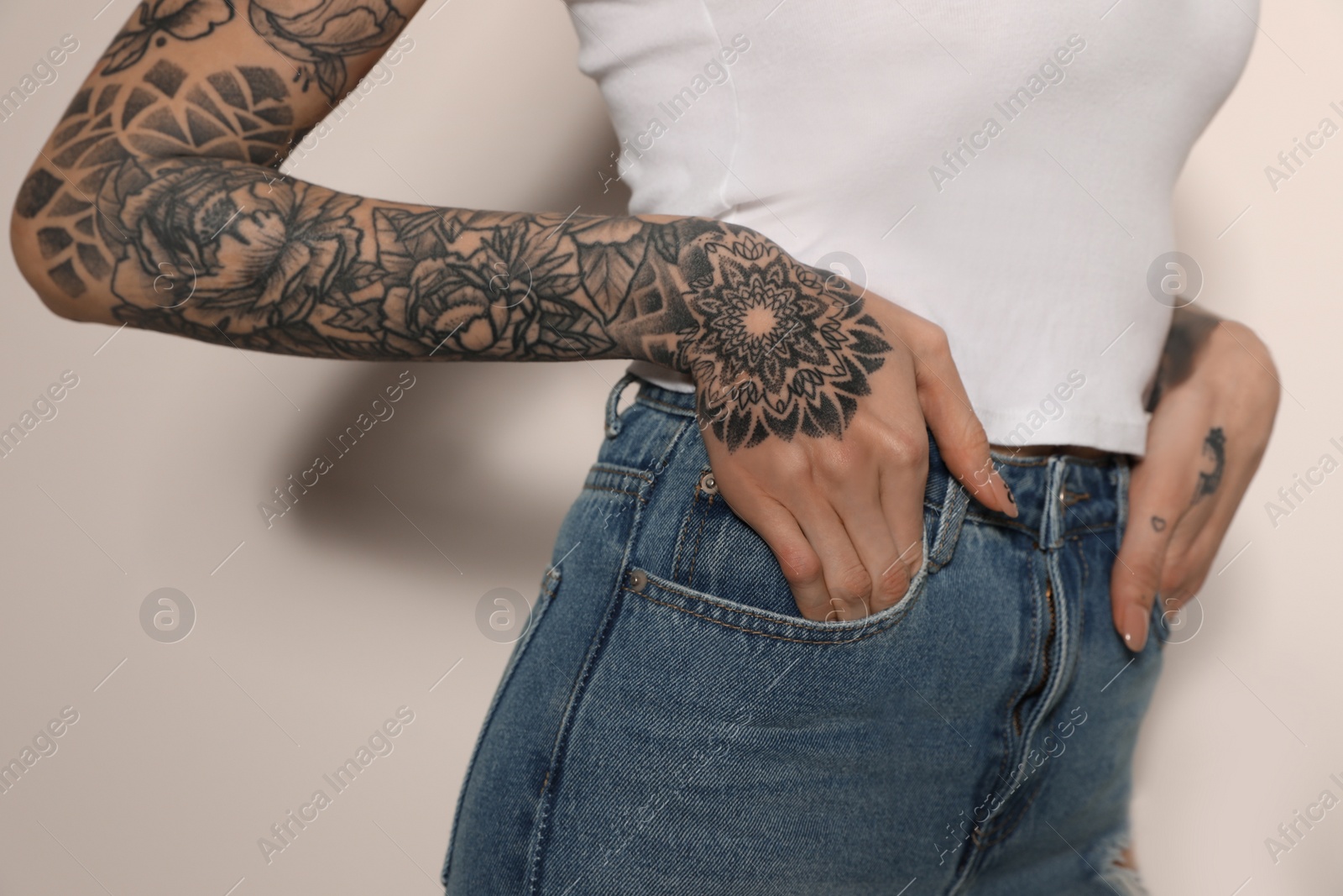 Photo of Woman with tattoos on arms against light background, closeup
