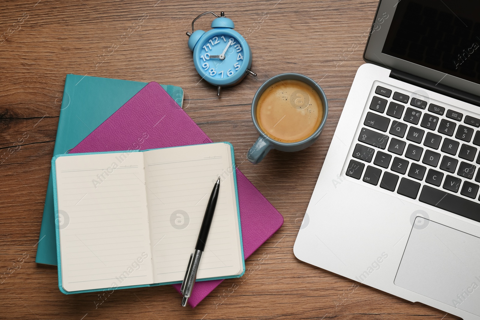 Photo of Modern laptop, cup of coffee and office stationery on wooden table, flat lay