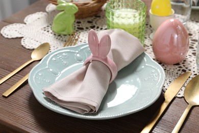 Photo of Festive table setting with napkin ring in shape of bunny ears, closeup. Easter celebration