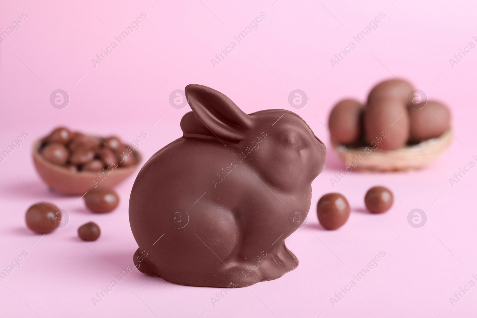 Photo of Chocolate Easter bunny and candies on pink background