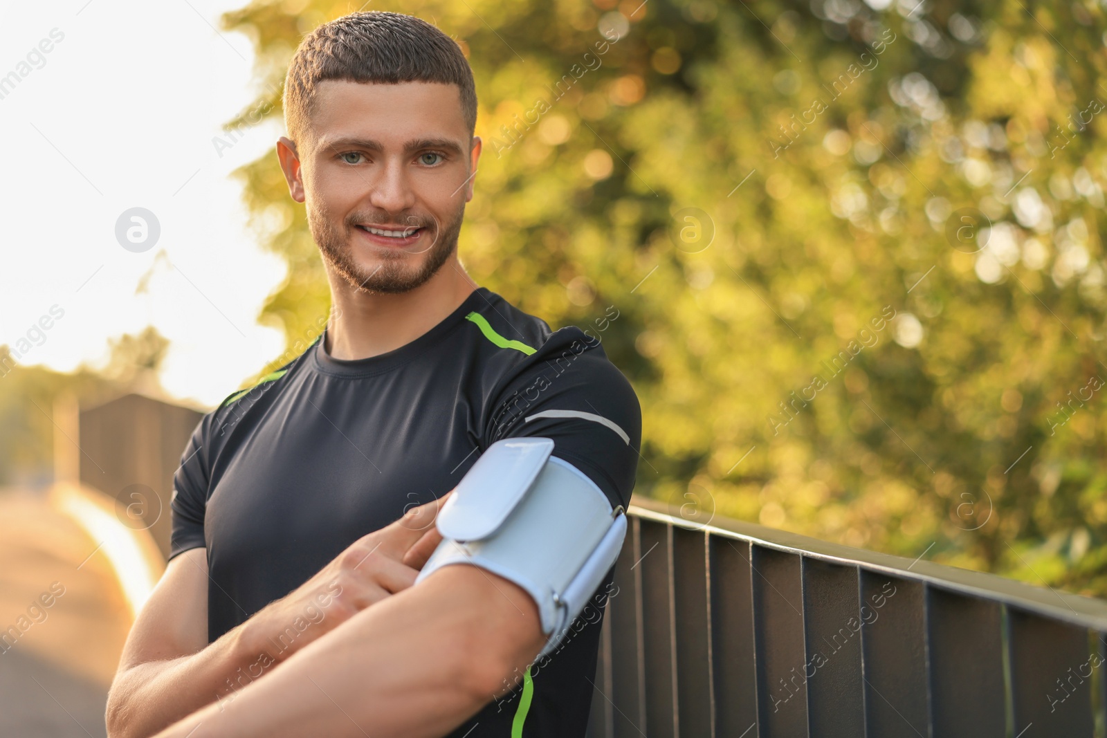 Photo of Attractive happy man checking blood pressure with modern monitor outdoors. Space for text