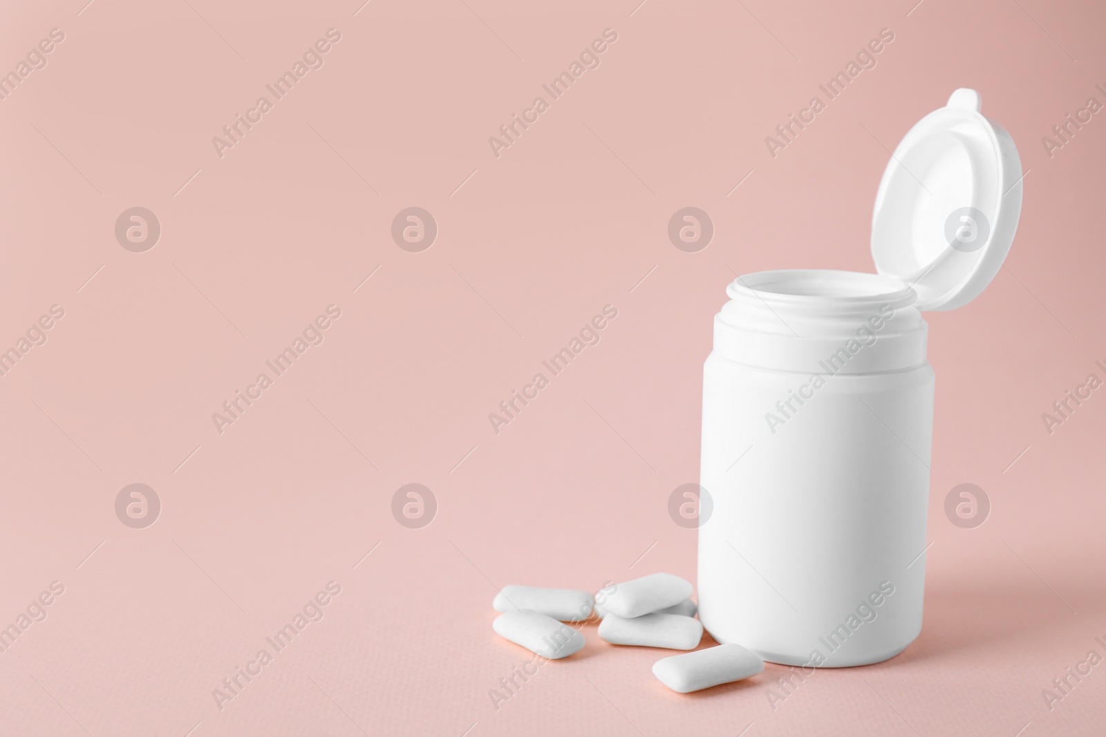 Photo of Jar with chewing gums on light pink background. Space for text