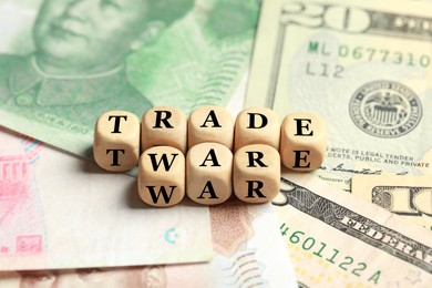 Photo of Wooden cubes with phrase Trade war on different banknotes, closeup