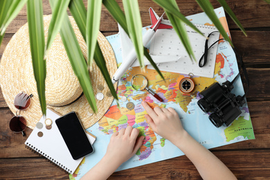 Woman with world map at table, top view. Travel during summer vacation