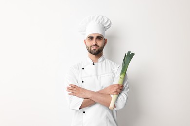 Professional chef holding leek on white background
