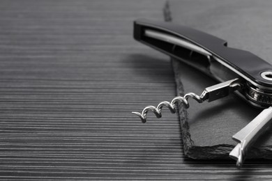 One corkscrew (sommelier knife) on black wooden table, closeup. Space for text