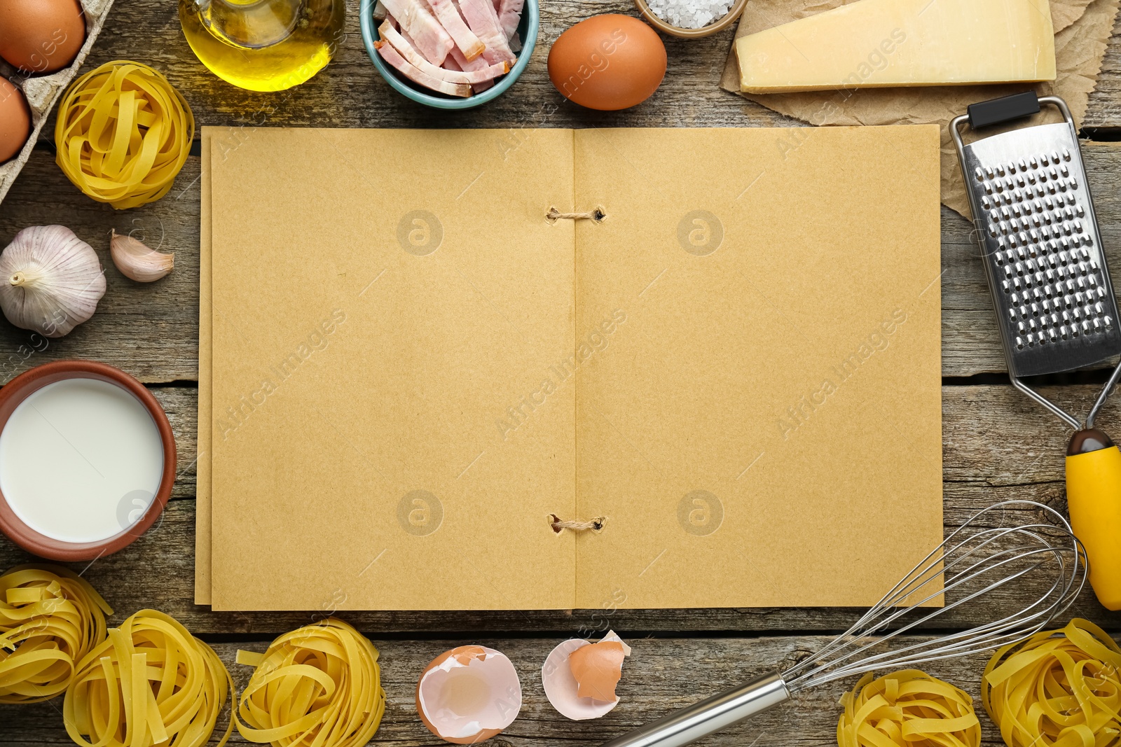 Photo of Blank recipe book surrounded by different ingredients on wooden table, flat lay. Space for text