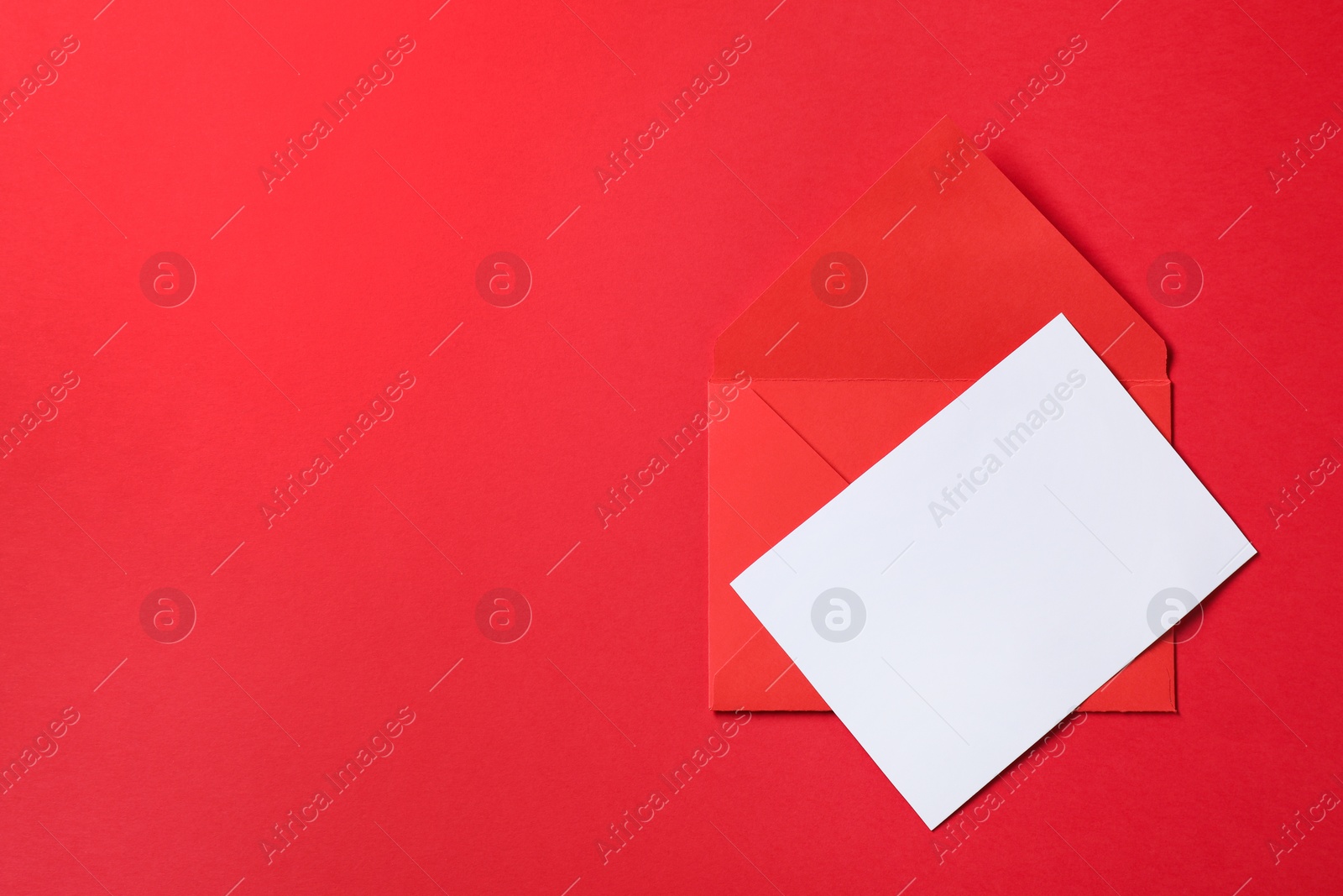 Photo of Letter envelope and card on red background, top view. Space for text