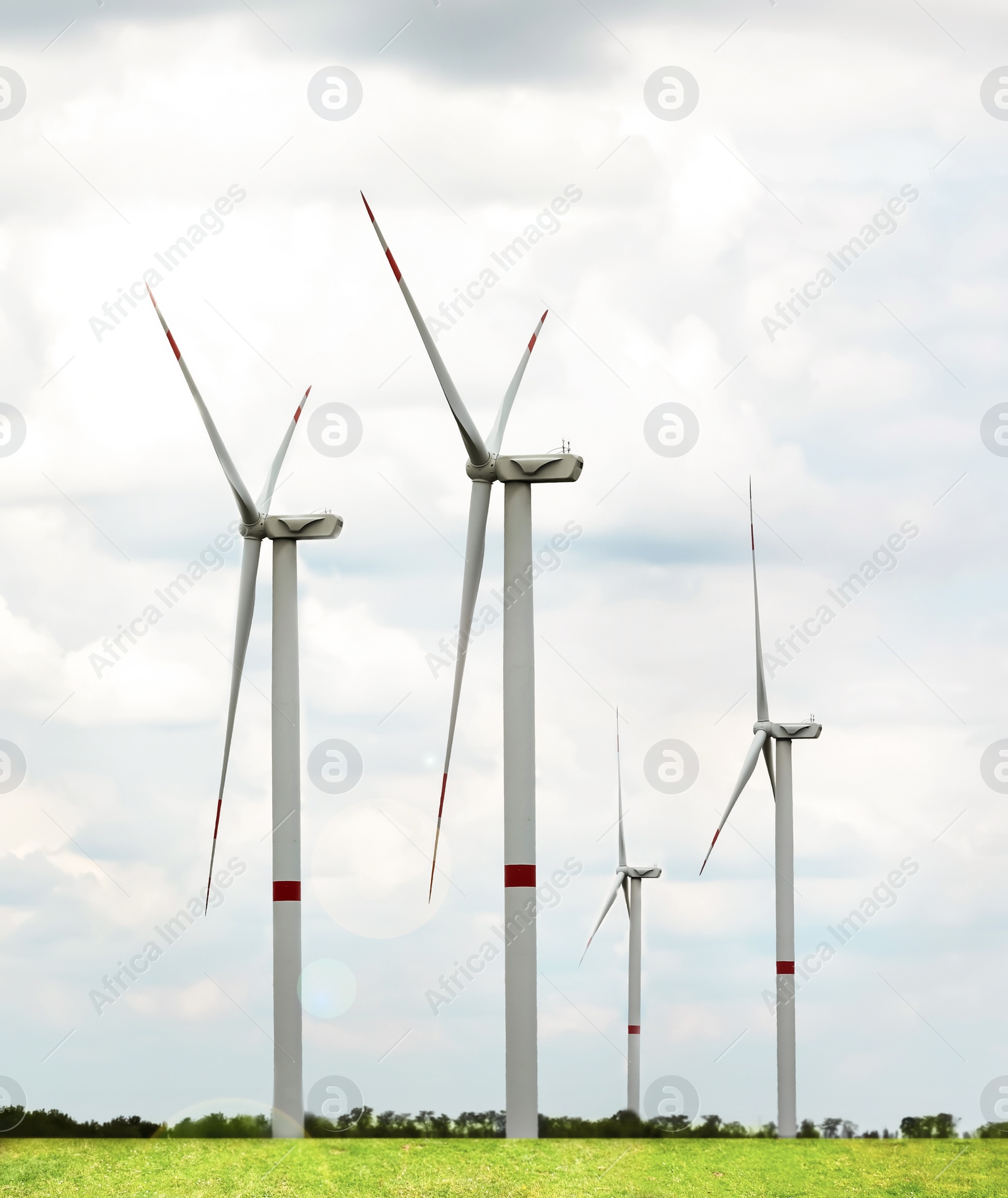 Image of Alternative energy source. Wind turbines in field under cloudy sky