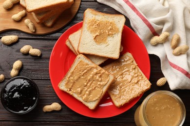 Photo of Delicious toasts with peanut butter, nuts and jam on dark wooden table, flat lay