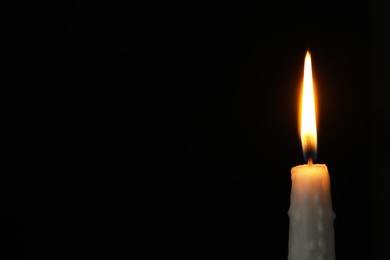 Photo of Burning candle on dark background, space for text. Symbol of sorrow