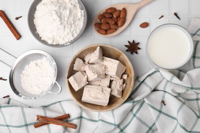Photo of Bowl with compressed yeast, flour and other ingredients on white tiled table, flat lay