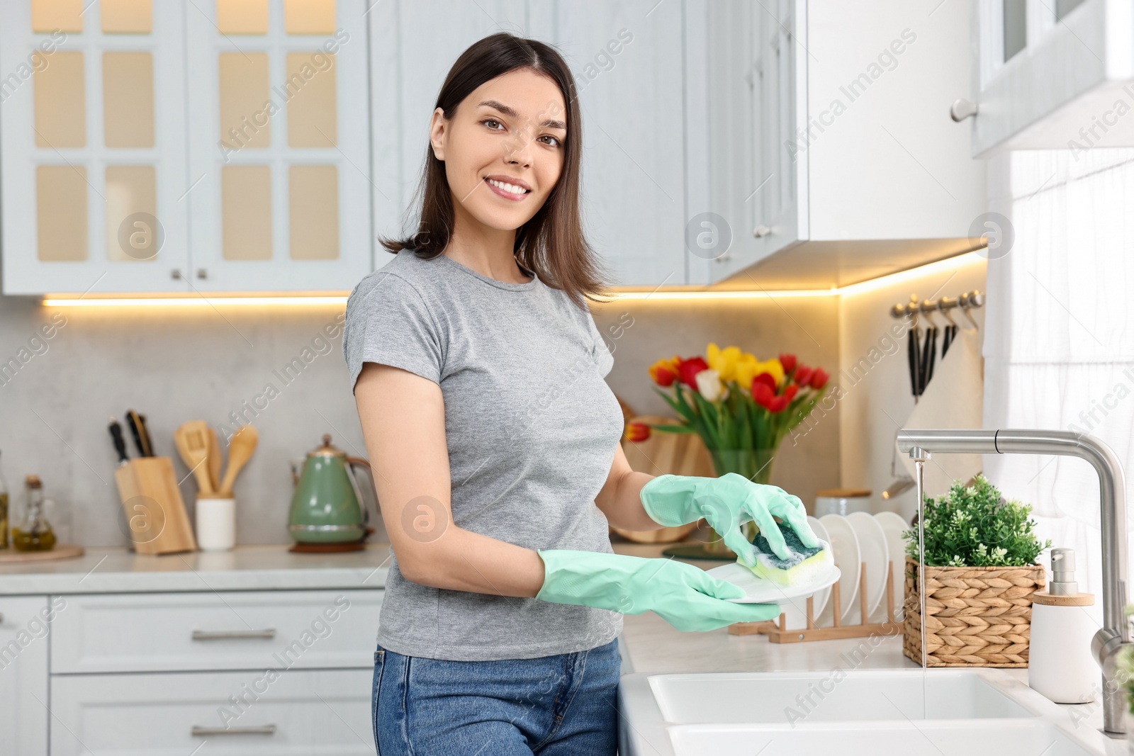 Photo of Woman washing dishes in kitchen sink. Cleaning chores