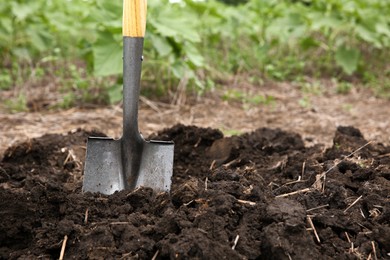 Shovel in soil outdoors, space for text