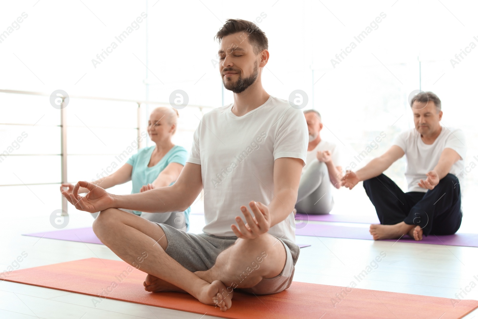 Photo of Group of people in sportswear practicing yoga indoors