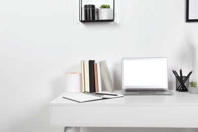 Photo of Cozy workspace with laptop and stationery on wooden desk at home. Space for text
