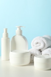 Different bath accessories on white table against light blue background