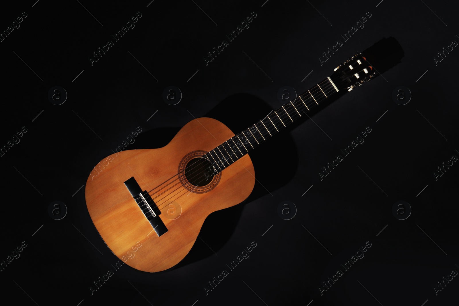 Photo of Acoustic guitar on black background, top view. Musical instrument