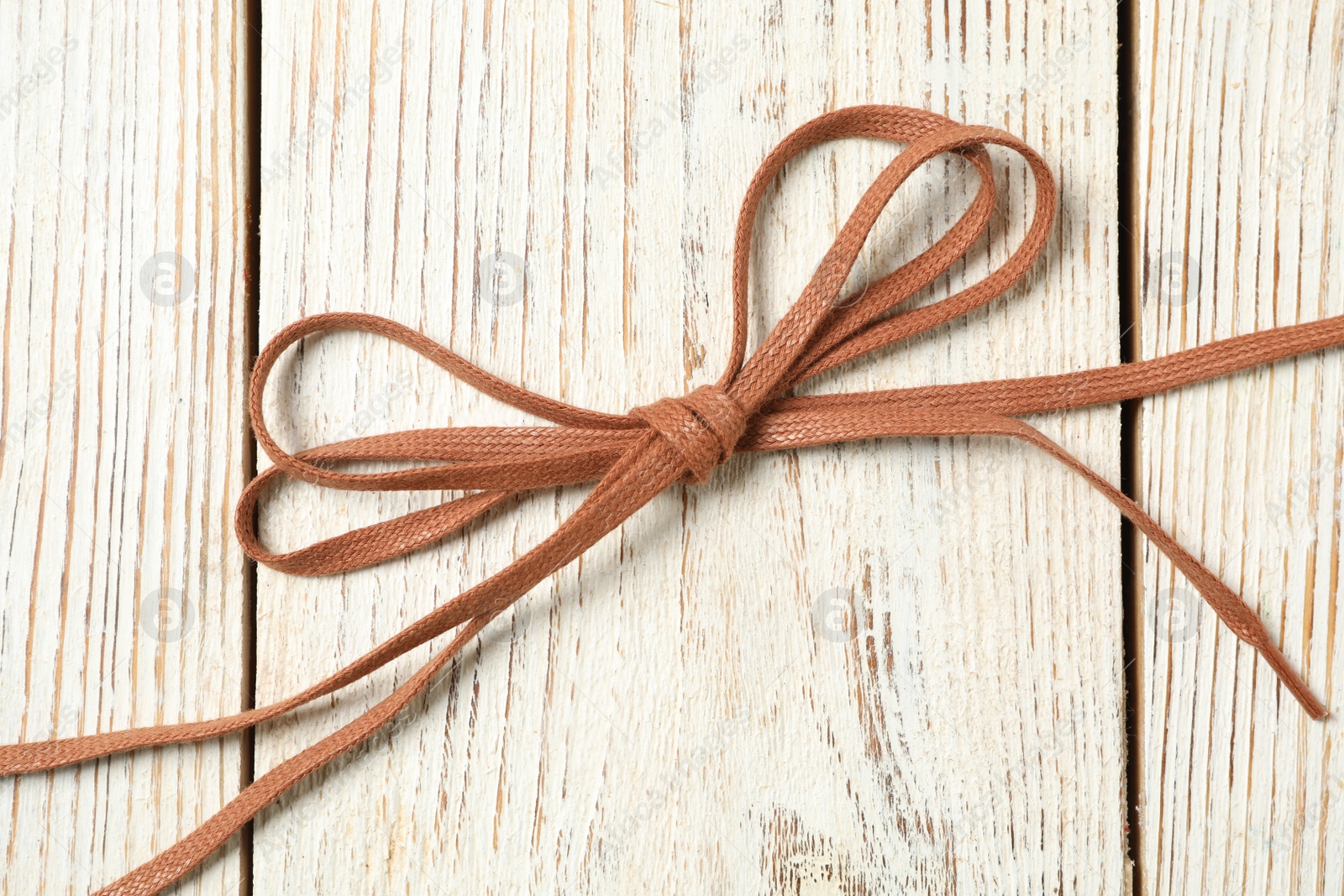 Photo of Brown shoelaces on white wooden background, top view