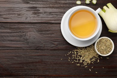 Photo of Fennel tea in cup, seeds and fresh vegetable on wooden table, flat lay. Space for text