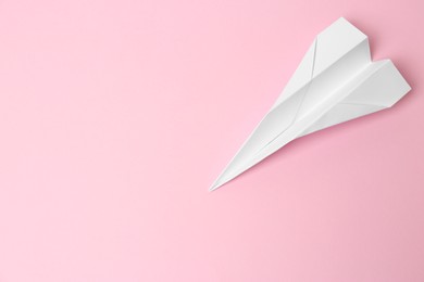 Photo of Handmade paper plane on pink background, top view. Space for text