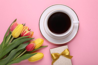 Photo of Cup of coffee, beautiful tulips and gift box on pink background, flat lay