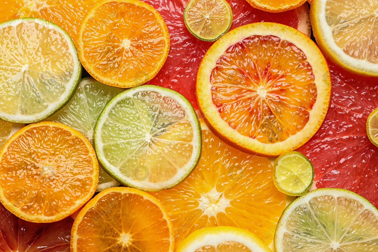 Photo of Slices of fresh citrus fruits as background, top view