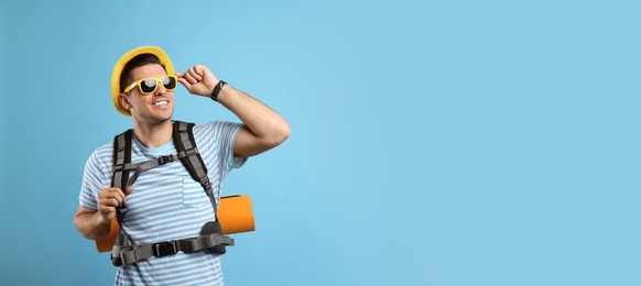 Male tourist with travel backpack on turquoise background
