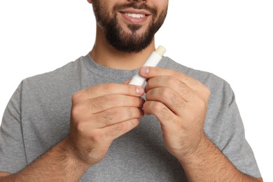 Young man with lip balm on white background, closeup