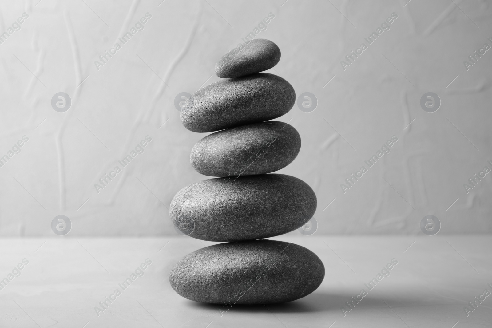 Photo of Stack of zen stones on table against light background