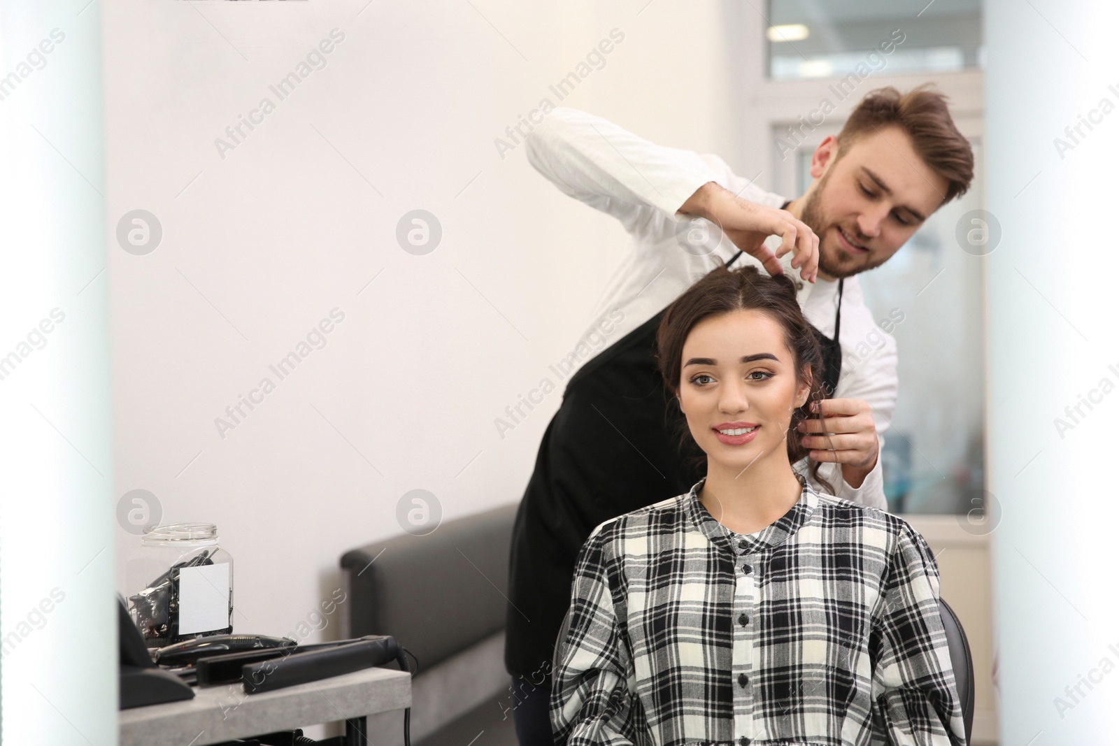 Photo of Professional male hairdresser working with client in salon