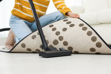 Young woman using vacuum cleaner at home, closeup
