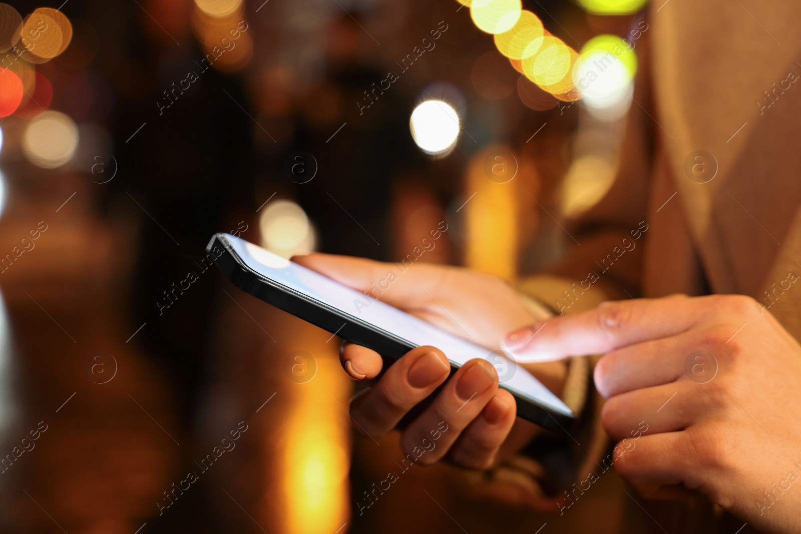 Photo of Woman using smartphone on night city street, closeup