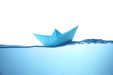 Image of Handmade blue paper boat floating on clear water against white background 