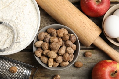 Nutmeg seeds and other ingredients for pastry on wooden table, flat lay