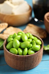 Photo of Fresh green soy beans and other organic products on light blue wooden table, closeup