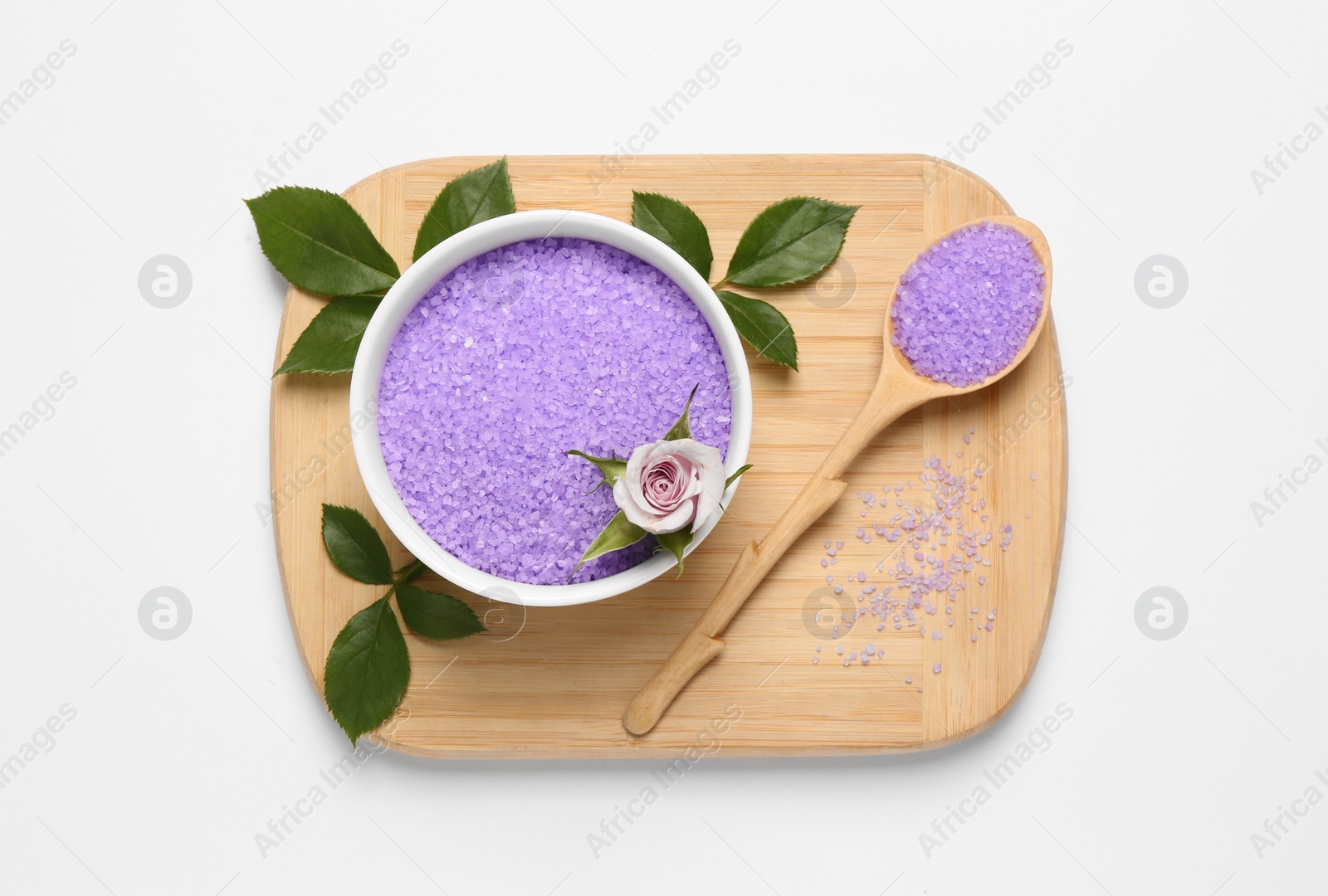 Photo of Bowl and spoon with sea salt, beautiful rose with green leaves on white background, top view