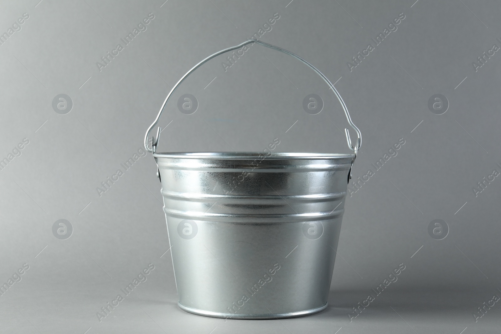 Photo of One shiny metal bucket on light grey background