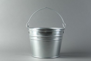 Photo of One shiny metal bucket on light grey background